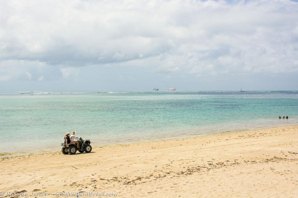 Imagem de casal de bugue ao fundo uma mar maravilhoso na Ilha de Itaparica.